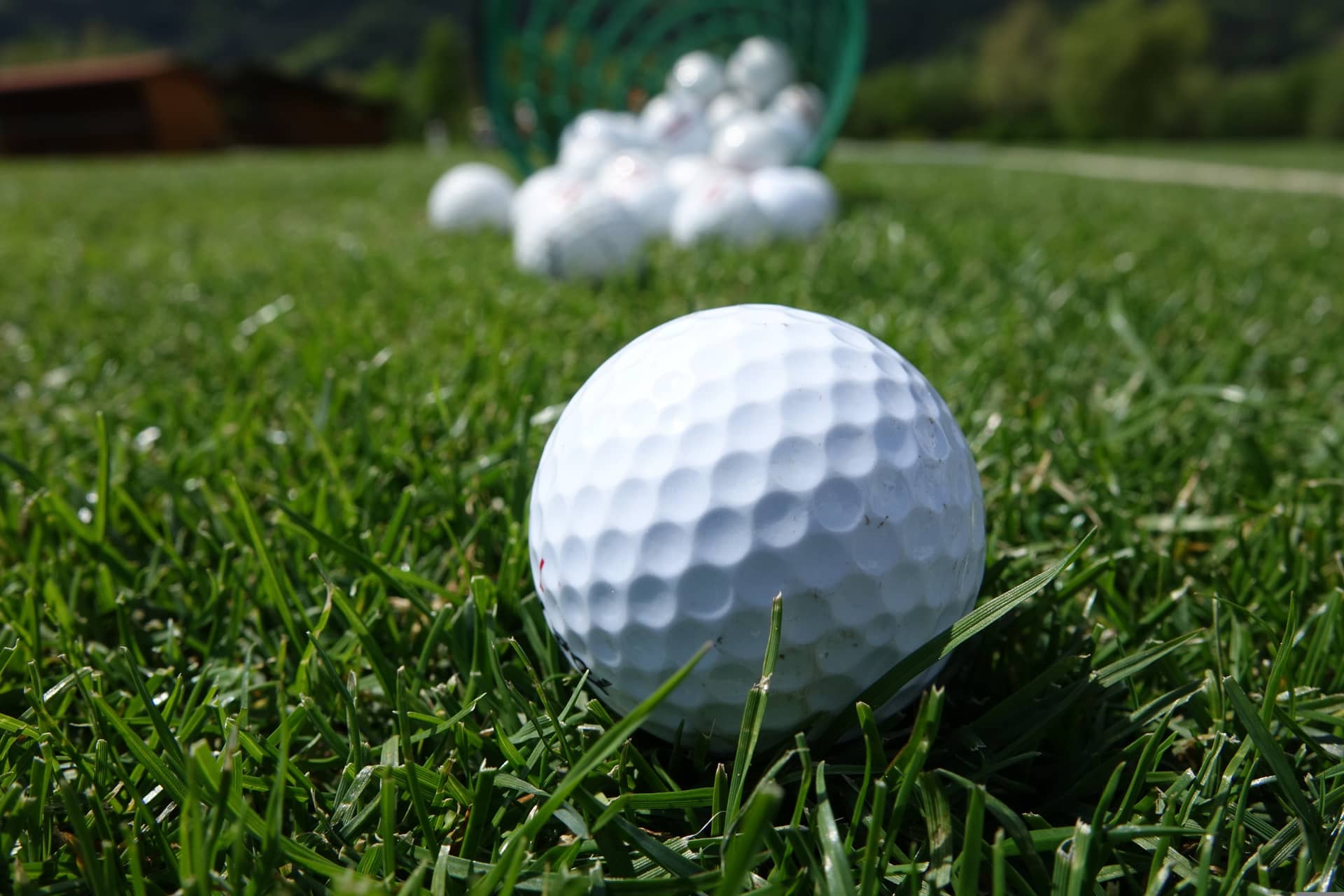 Range balls spilling out of a bucket onto short grass